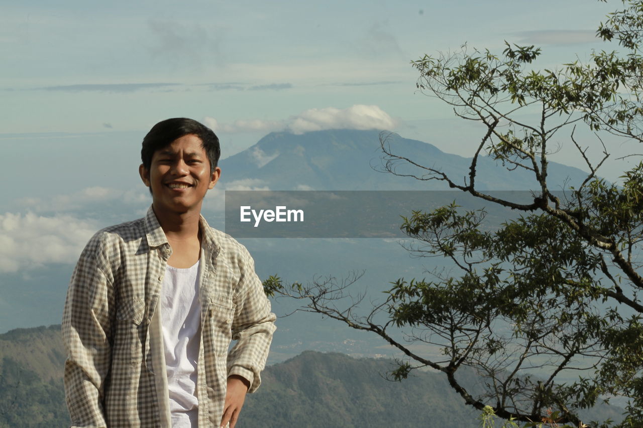 Young man standing on mountain against sky