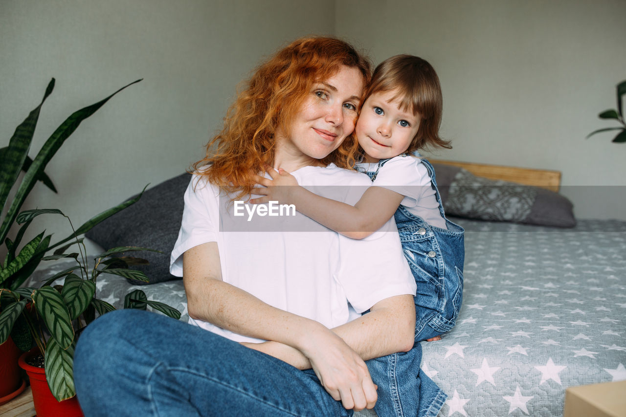 Young mother and child have fun and fool around at home on the bed