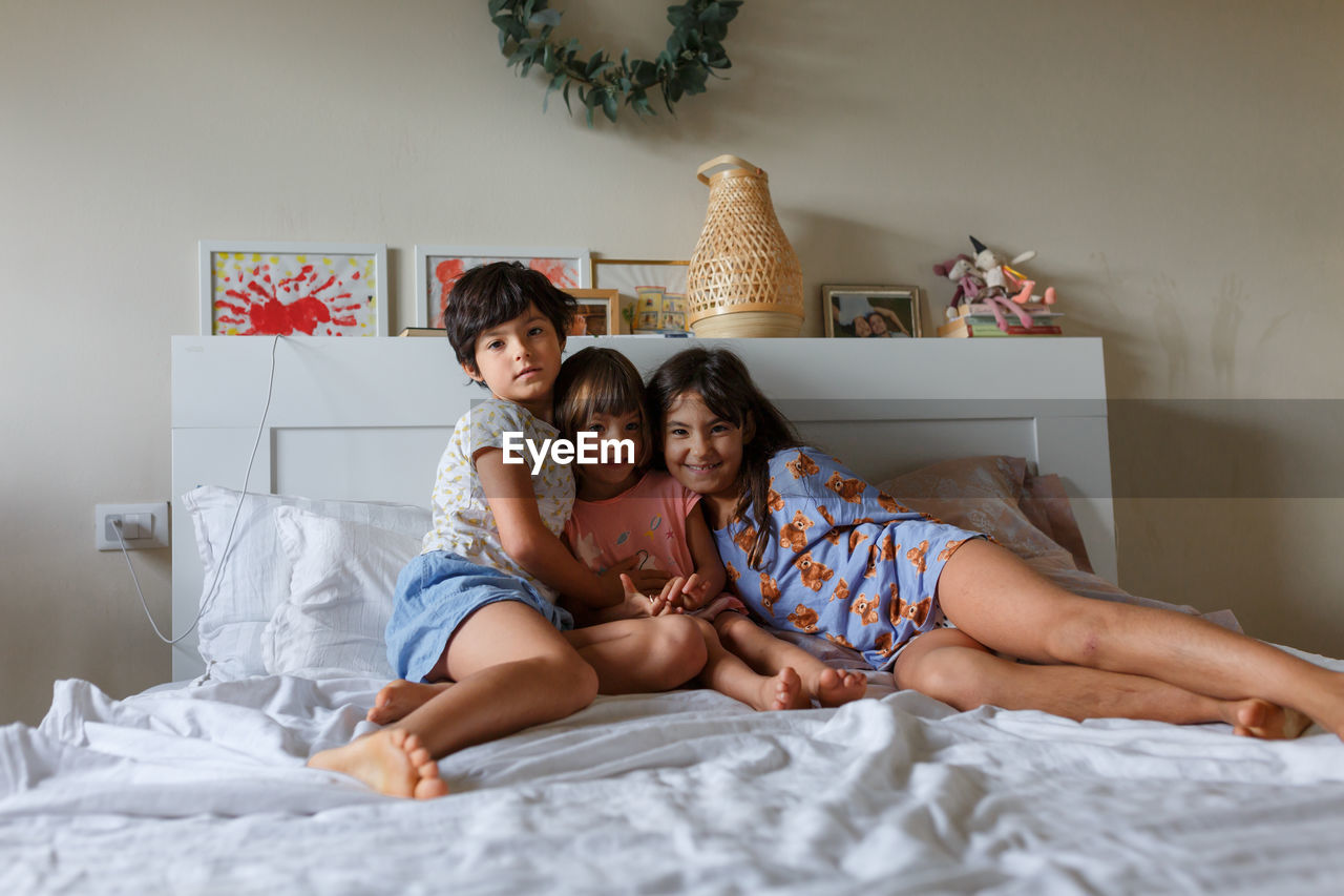 Group of smiling children laying in parent's bed posing for photo