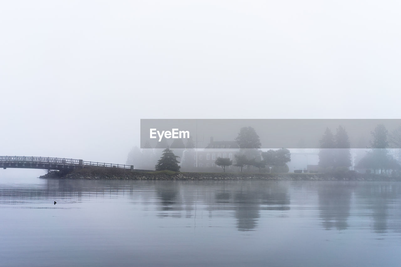 Bridge over river during foggy weather