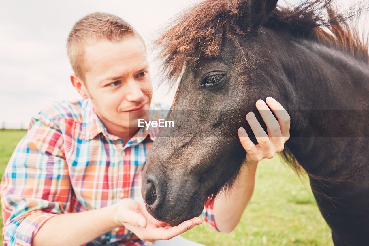 Man by horse at ranch