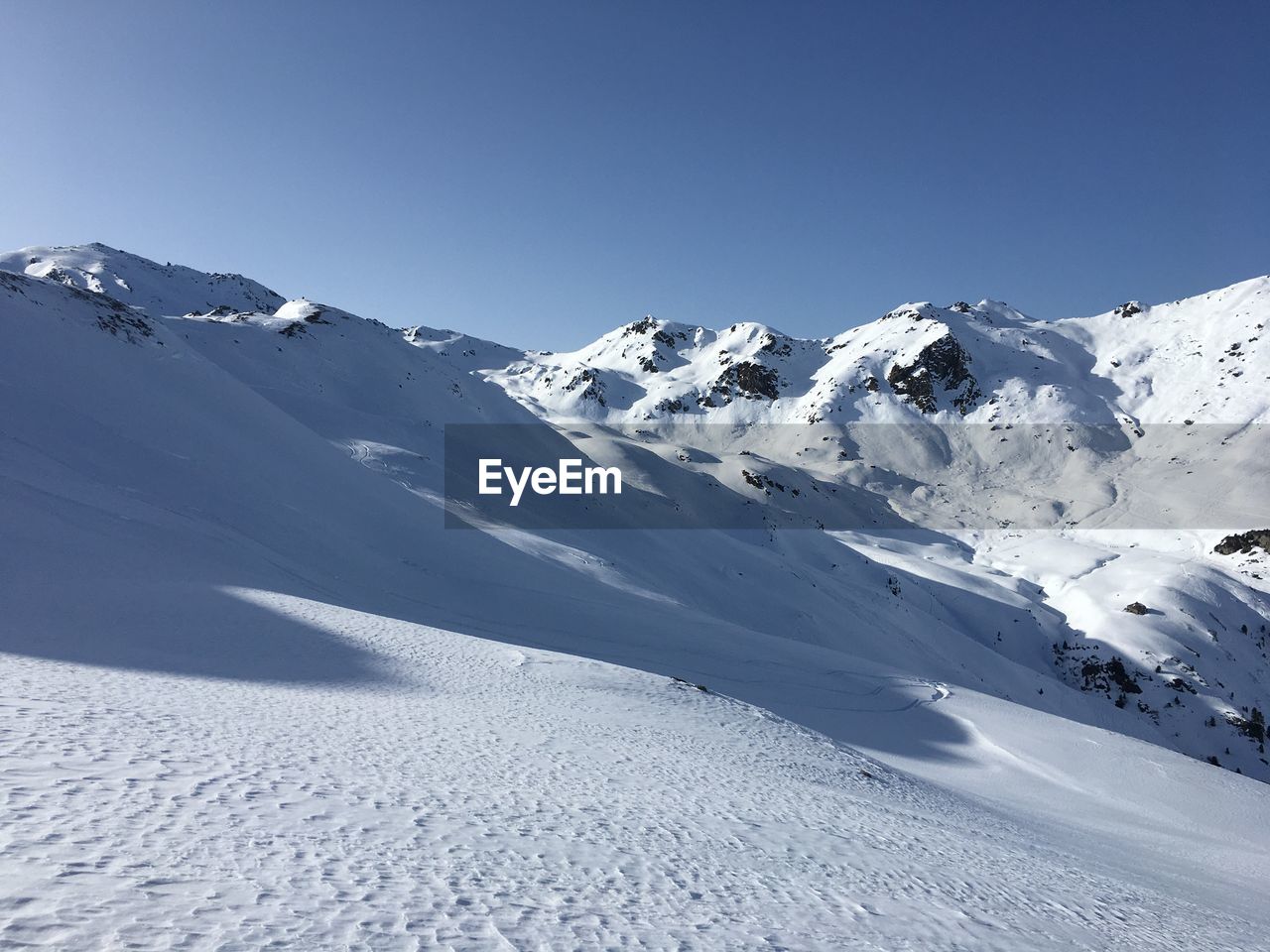 Scenic view of snowcapped mountains against clear blue sky