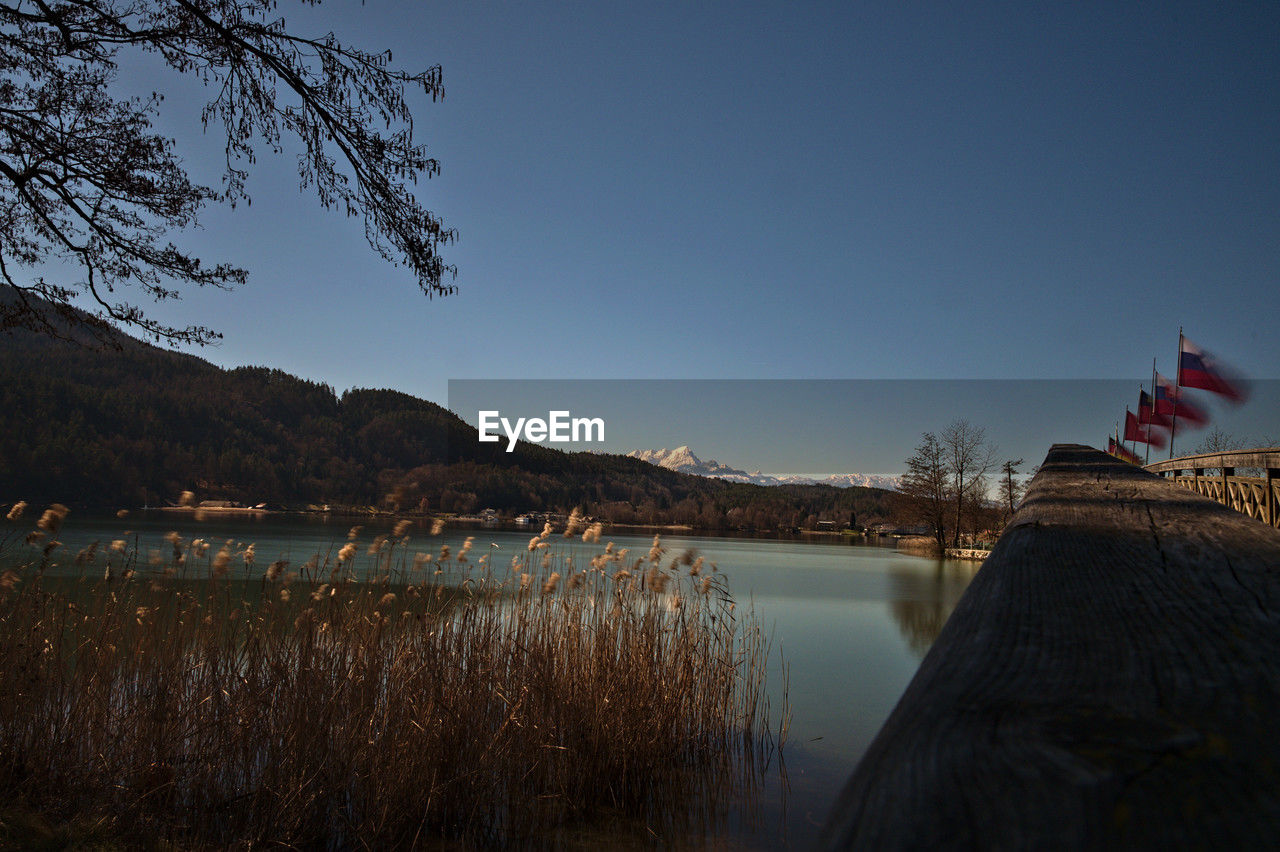 reflection, evening, nature, sky, dusk, water, lake, mountain, sunset, landscape, tree, no people, plant, travel destinations, environment, scenics - nature, flag, architecture, beauty in nature, tranquility, travel, night, clear sky, tranquil scene, land, outdoors, patriotism, horizon, blue, body of water, mountain range, cloud, tourism, built structure