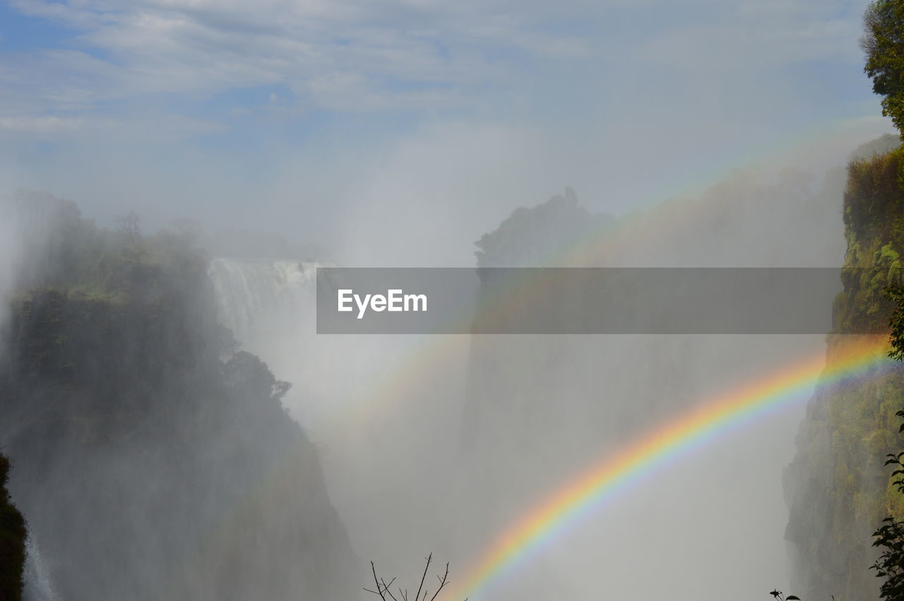 RAINBOW OVER MOUNTAIN AGAINST SKY