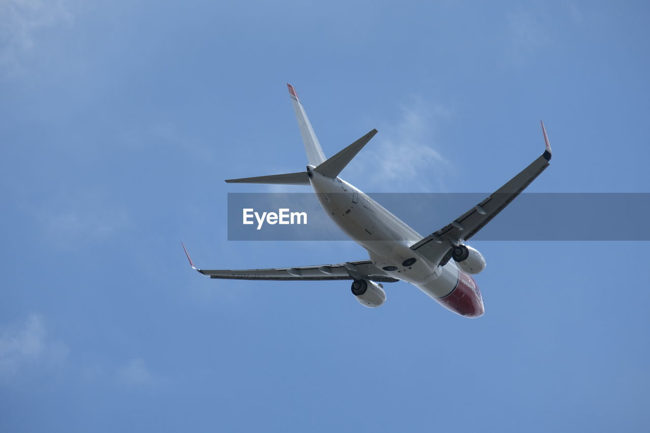 LOW ANGLE VIEW OF AIRPLANE AGAINST BLUE SKY