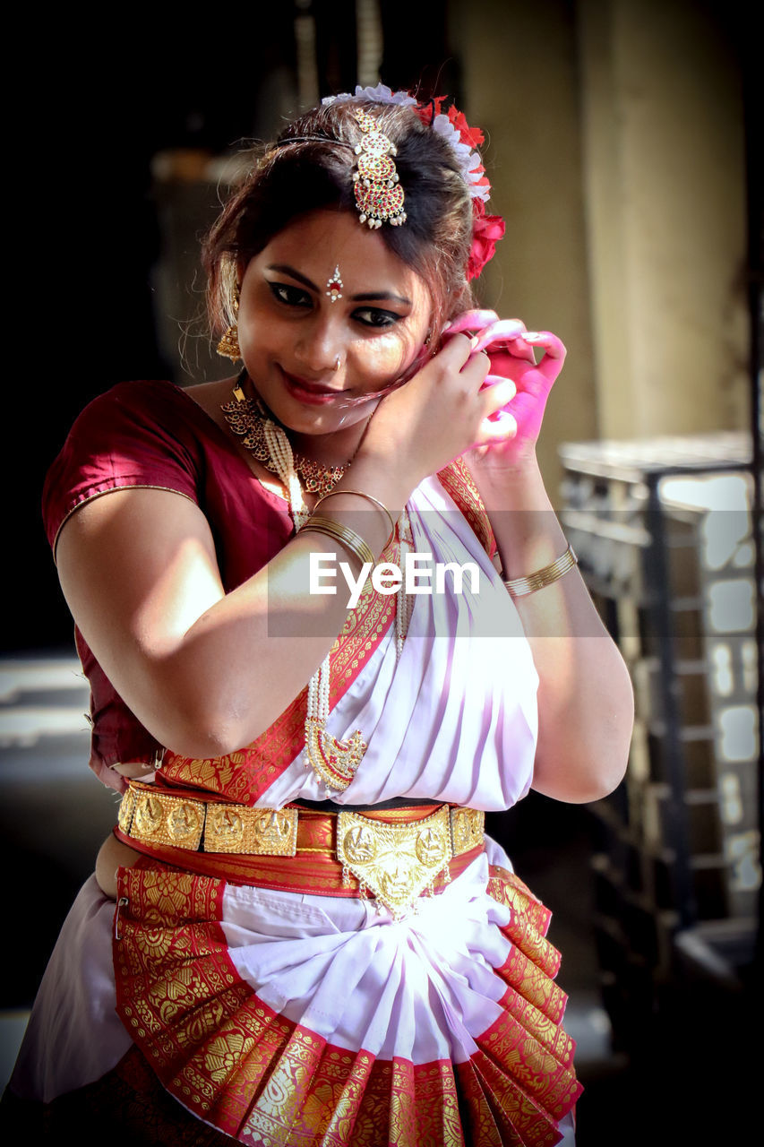 Woman in traditional clothing wearing earring at home