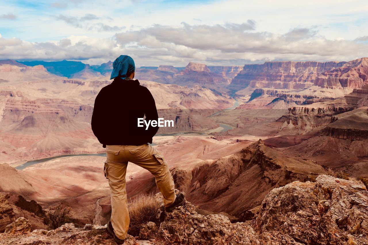 Rear view of man looking at mountains against sky