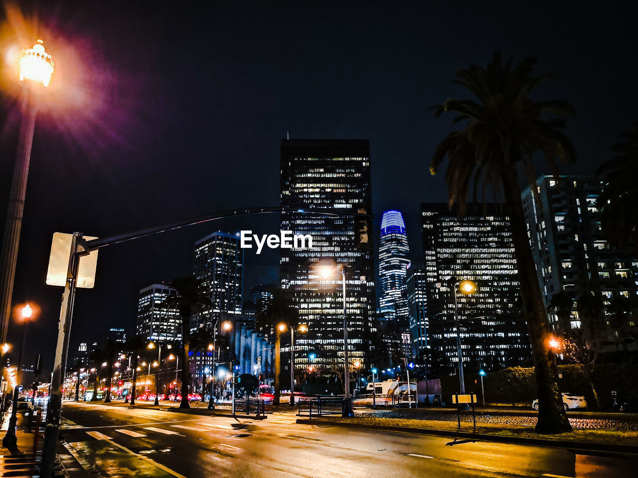Illuminated city street against sky at night