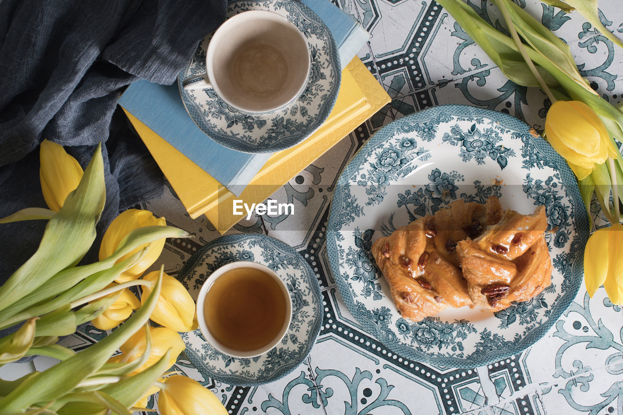 Flat lay food, sweet puff, tea in a vintage porcelain cup and a stack of books
