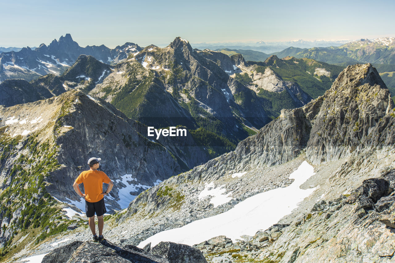 Trail runner looks out at view from the summit of a mountain.