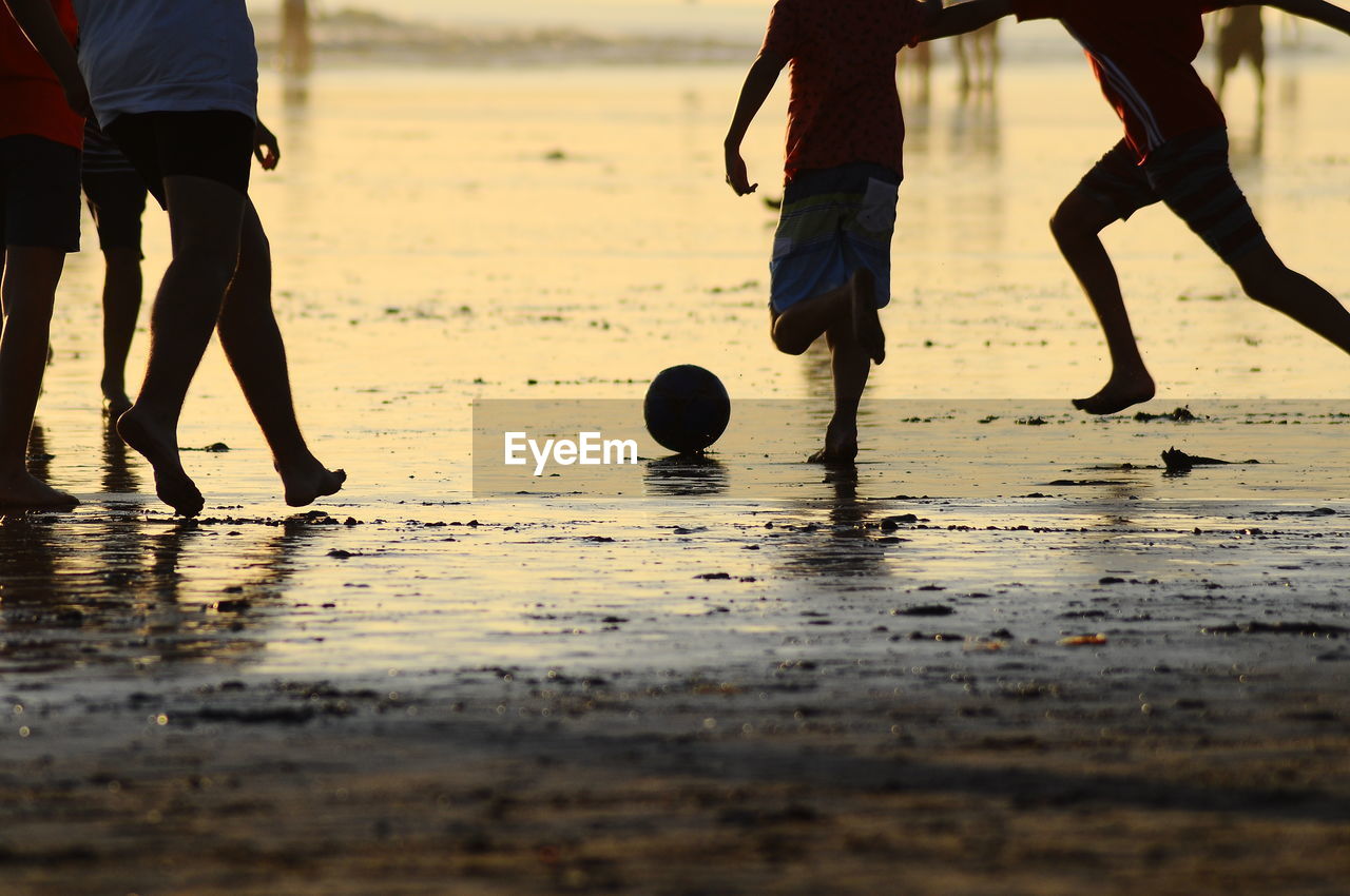 Low section of boys playing on sand at beach