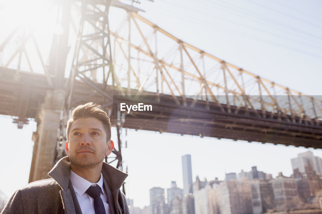 Portrait of young businessman standing near a bridge in an urban environment