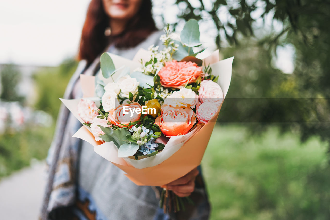 CLOSE-UP OF WOMAN HOLDING BOUQUET OF RED ROSE