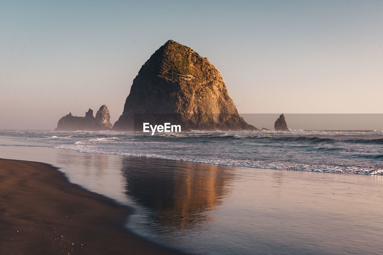 Rock formation on beach against clear sky