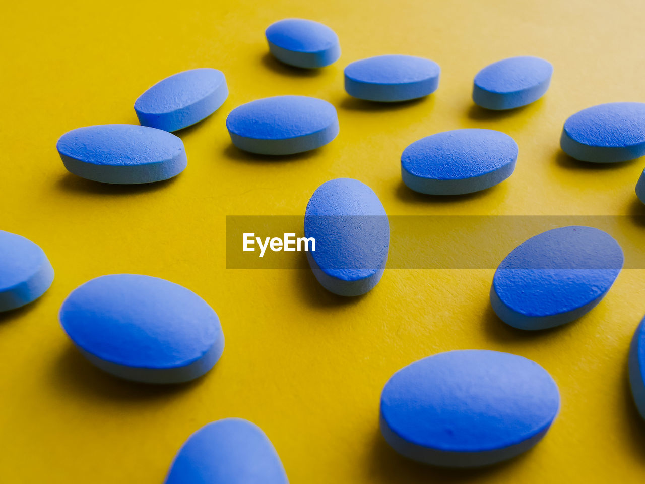 Generic blue pills on yellow backdrop