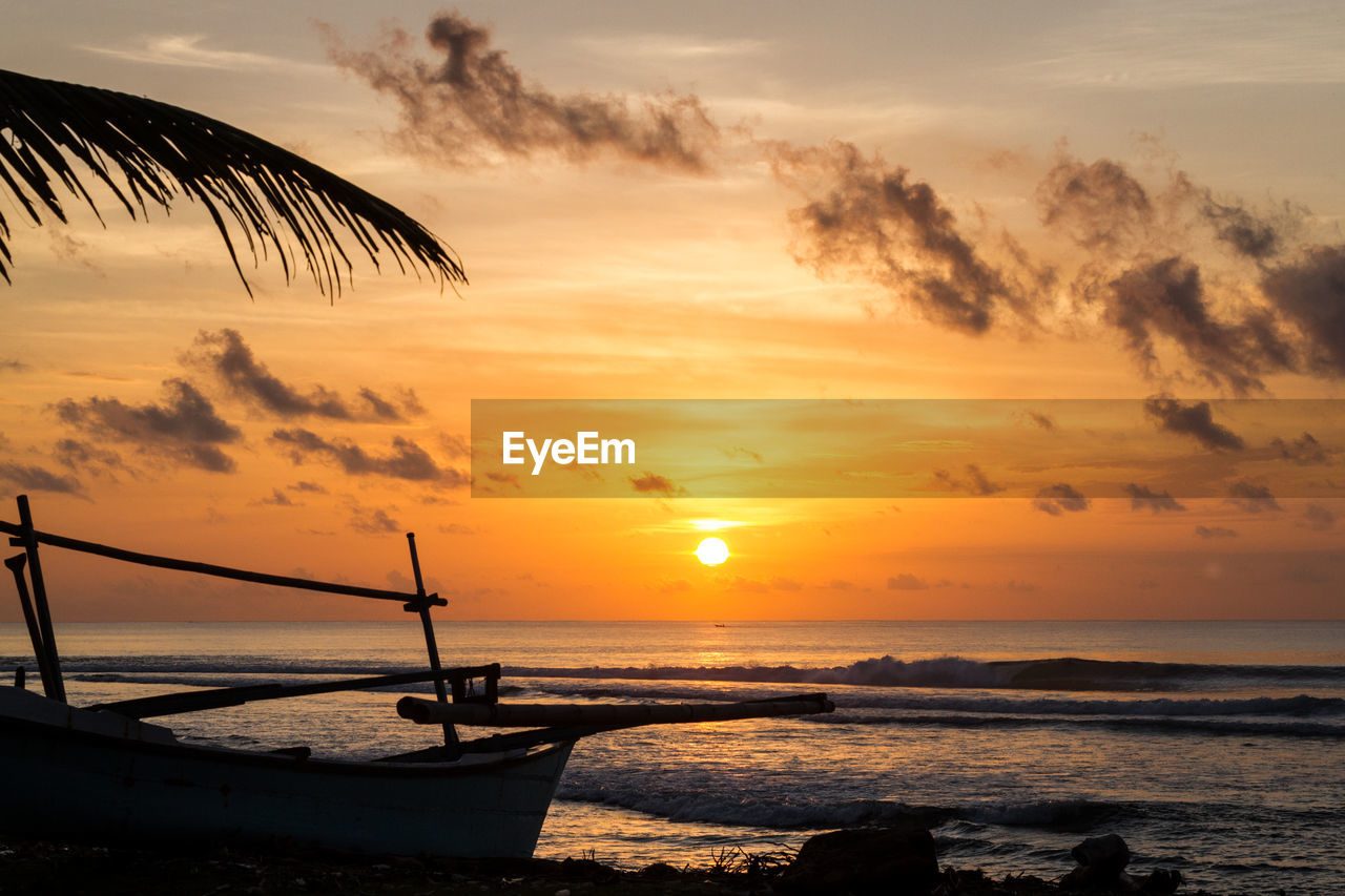 Boat anchored by sea at dusk