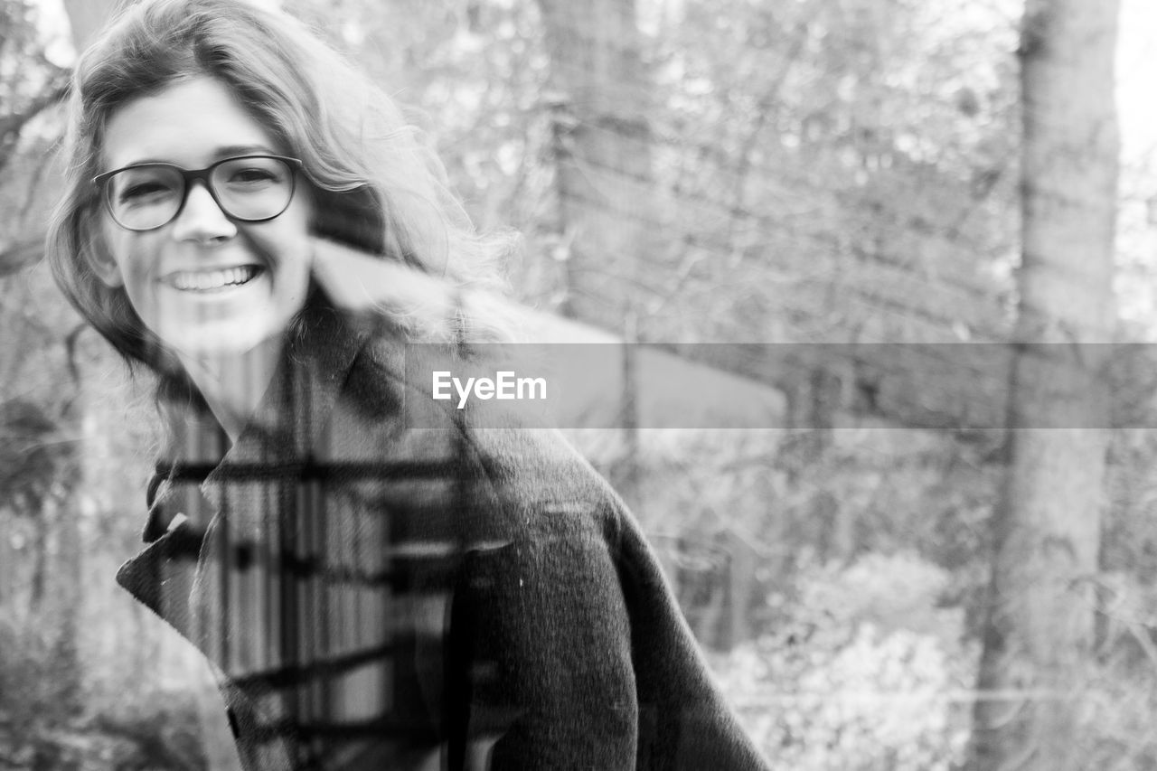 Cheerful woman wearing eyeglasses seen through glass window