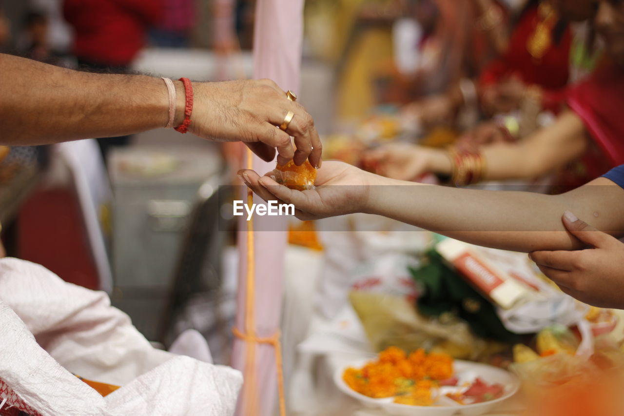 Cropped hand of priest giving sweet food to person at temple