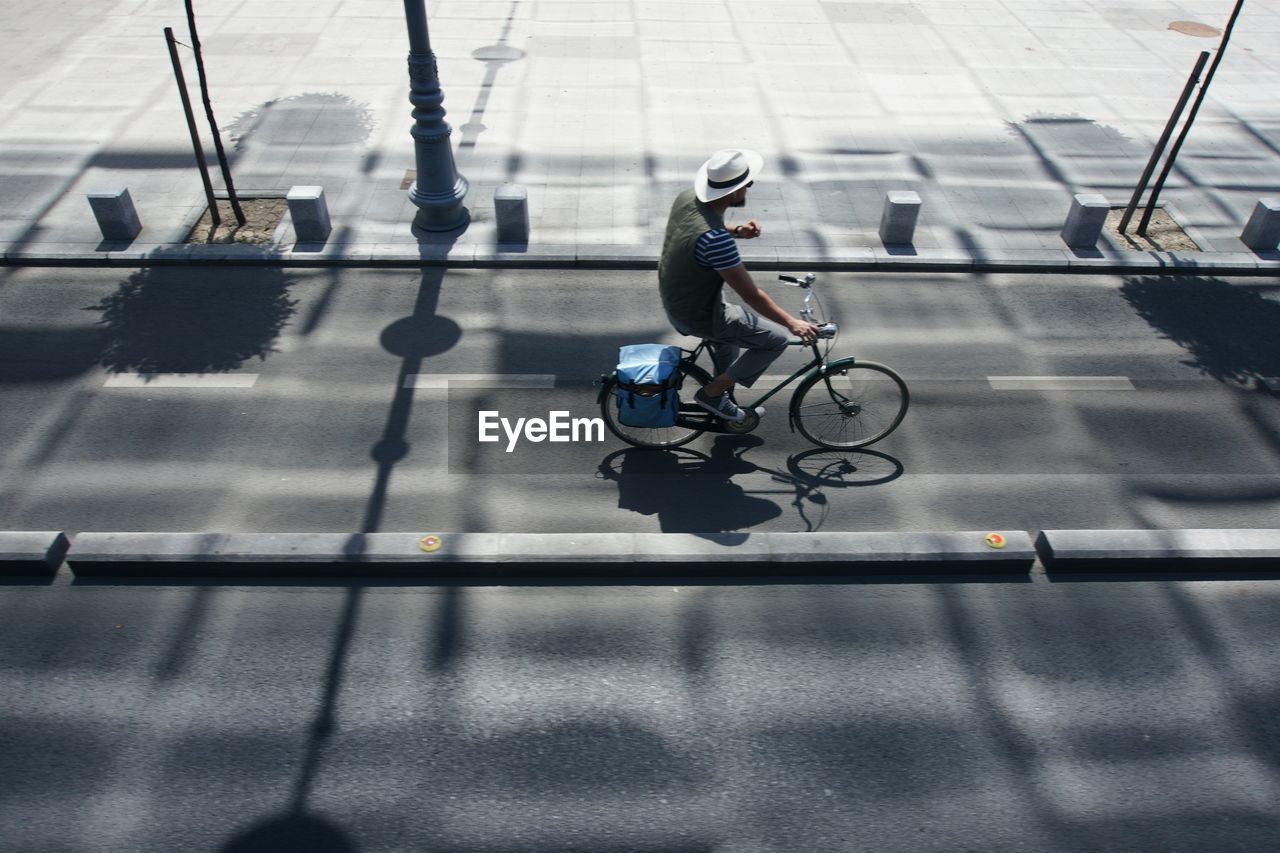 High angle view of man riding bicycle on road during sunny day