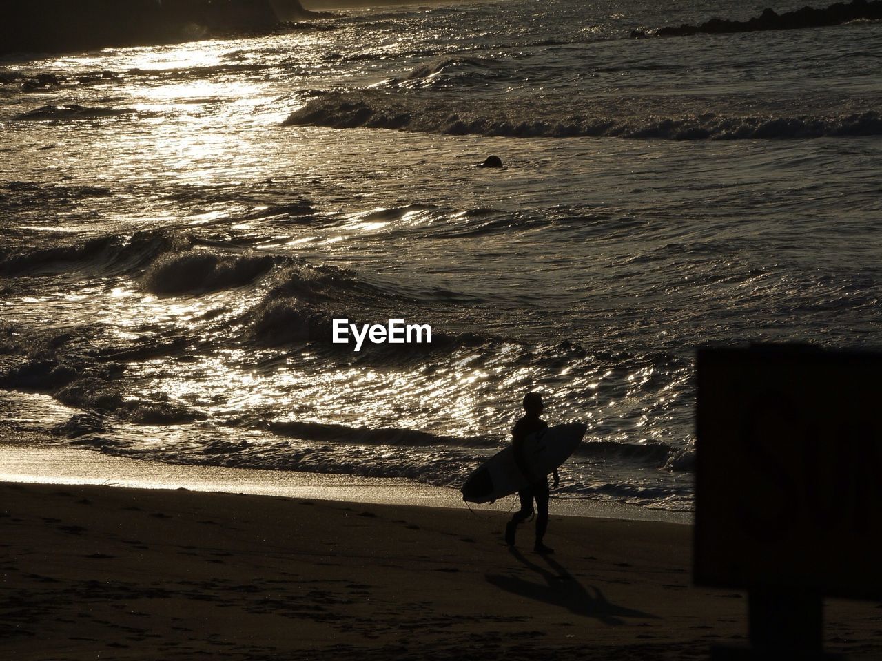 Silhouette of surfer walking on beach