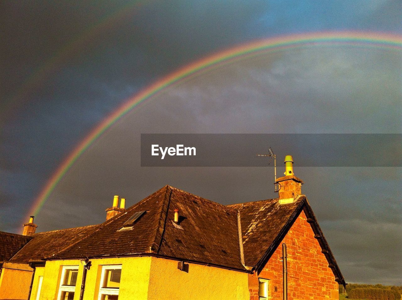 Rainbow over house against sky