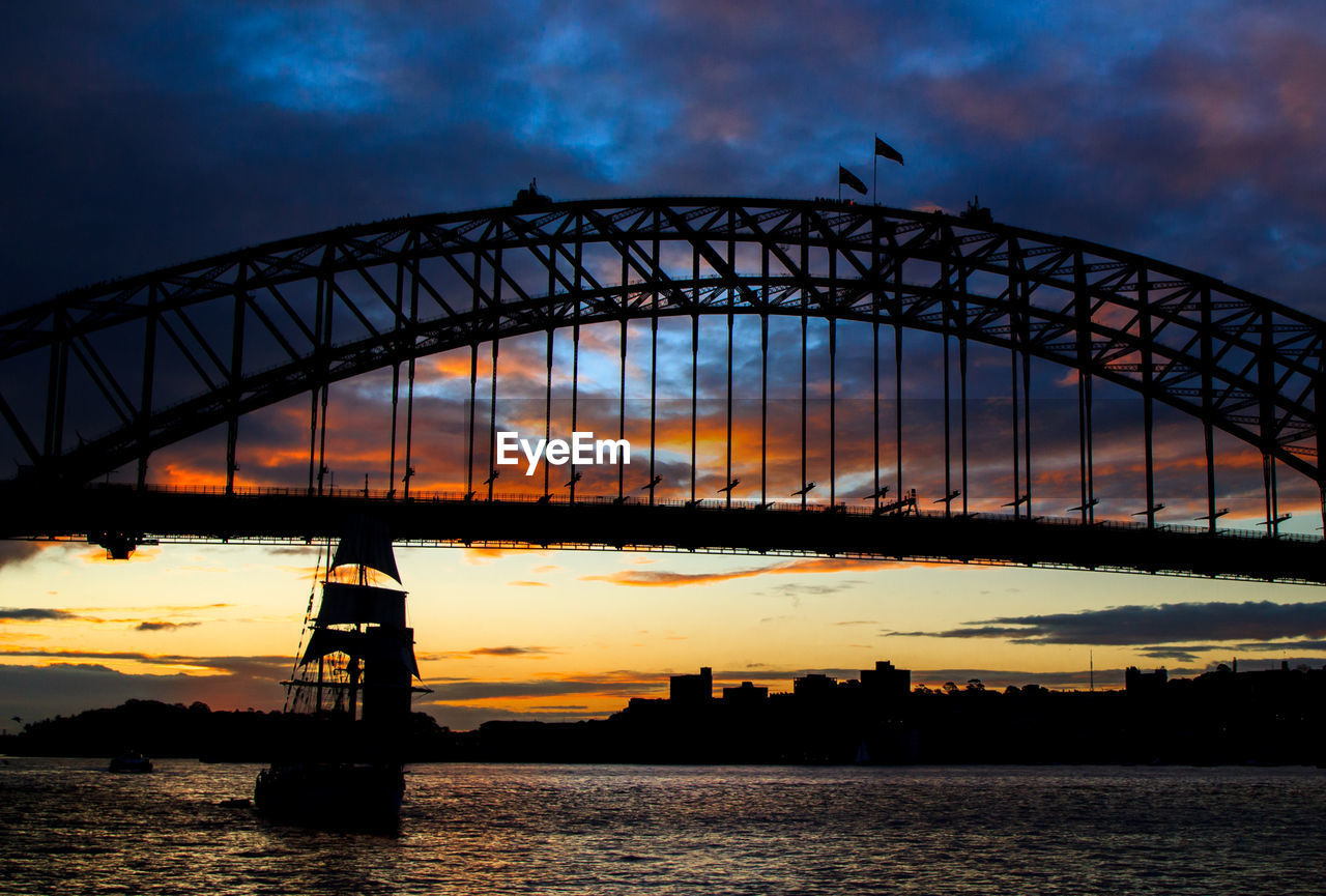 Silhouette sailing ship in bay of water against sydney harbor bridge