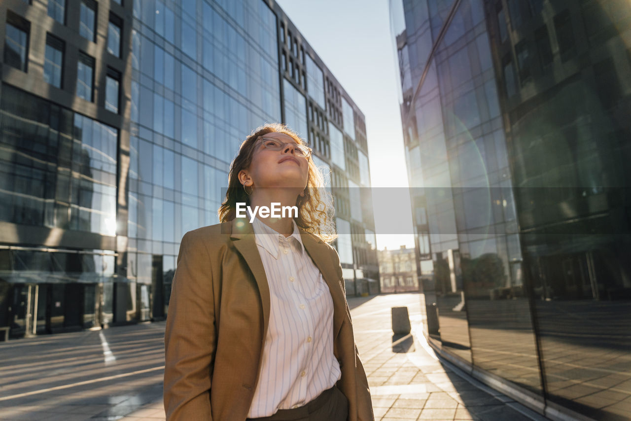 Thoughtful businesswoman looking up on sunny day