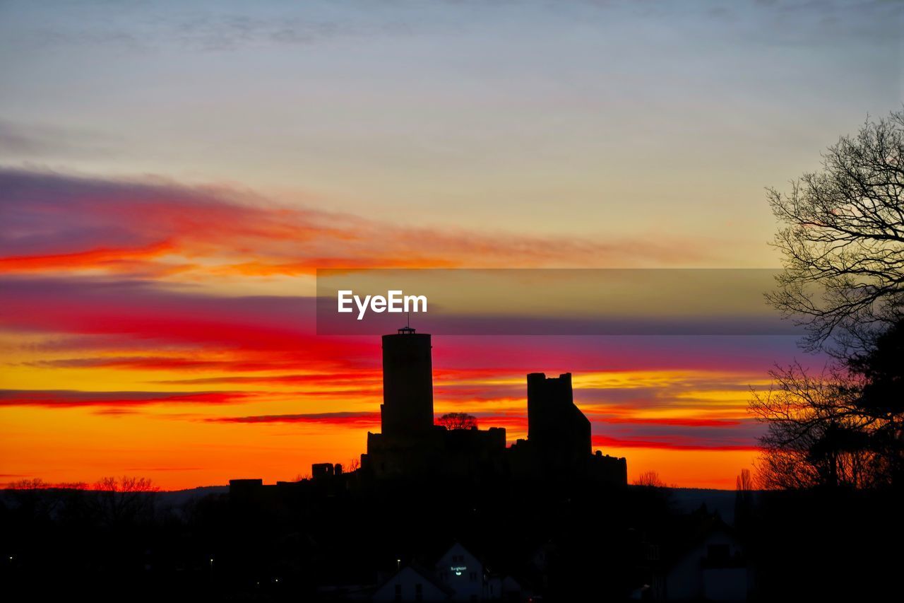 Silhouette of buildings against cloudy sky during sunset