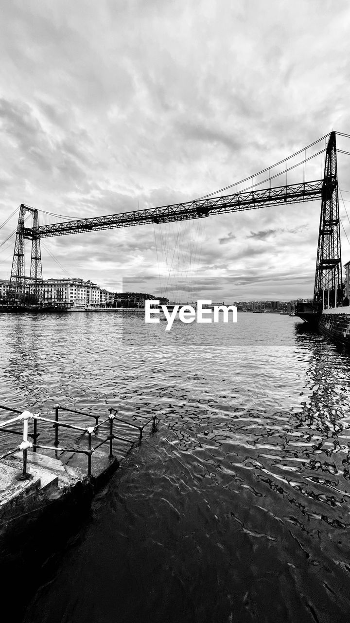 VIEW OF SUSPENSION BRIDGE AGAINST CLOUDY SKY