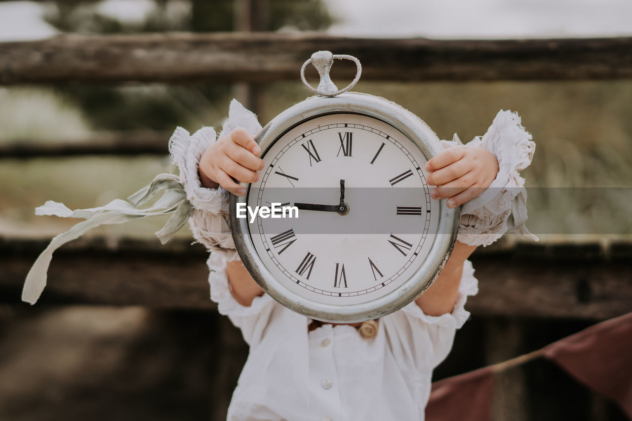 Child girl holding clock in her hands