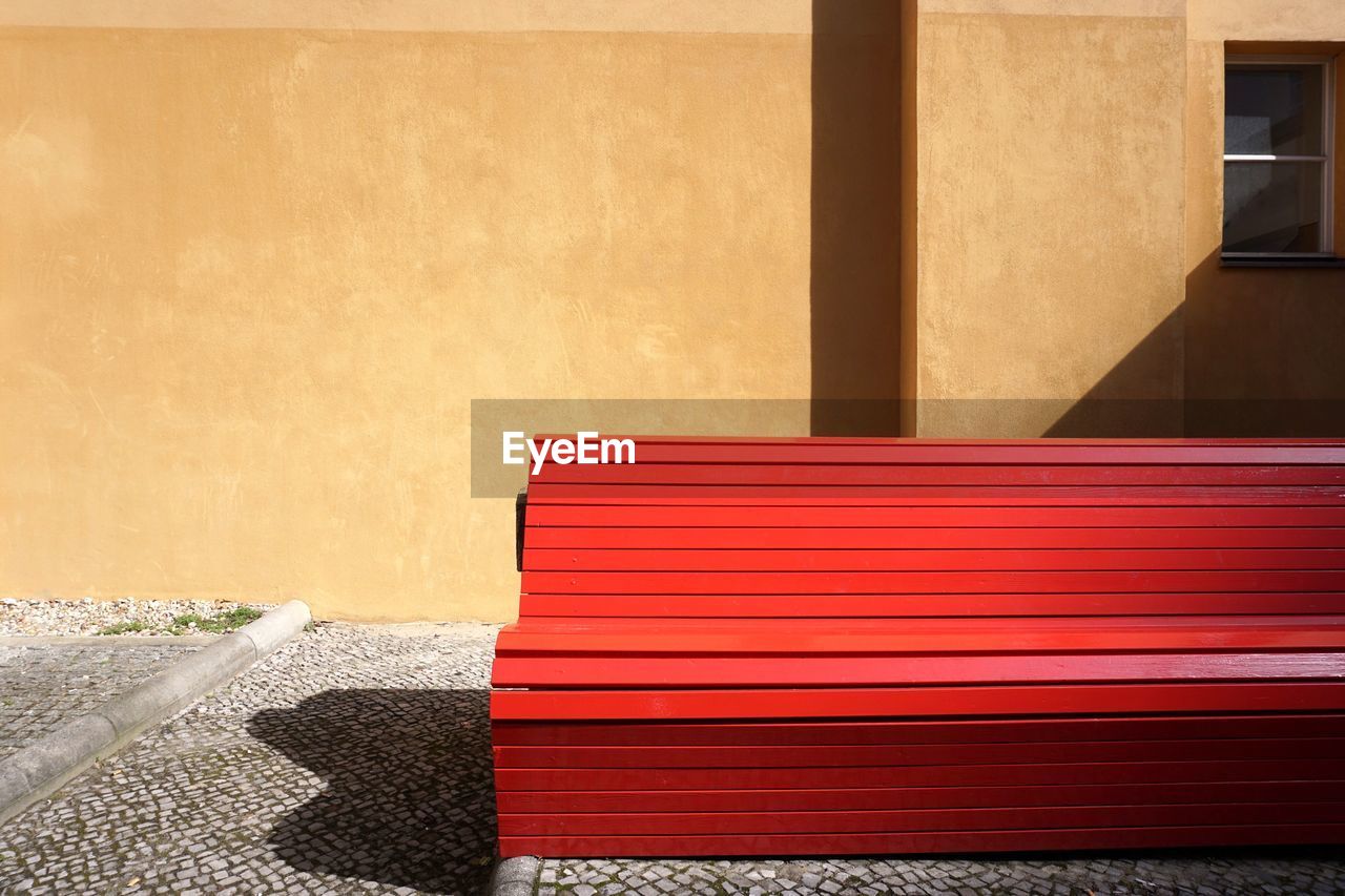 Empty red bench against wall