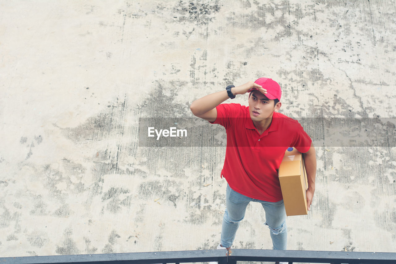 High angle view of delivery man holding package while standing on footpath