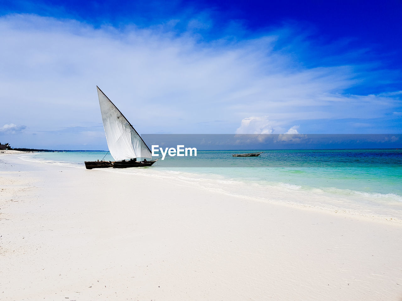 Sailboat on beach against blue sky