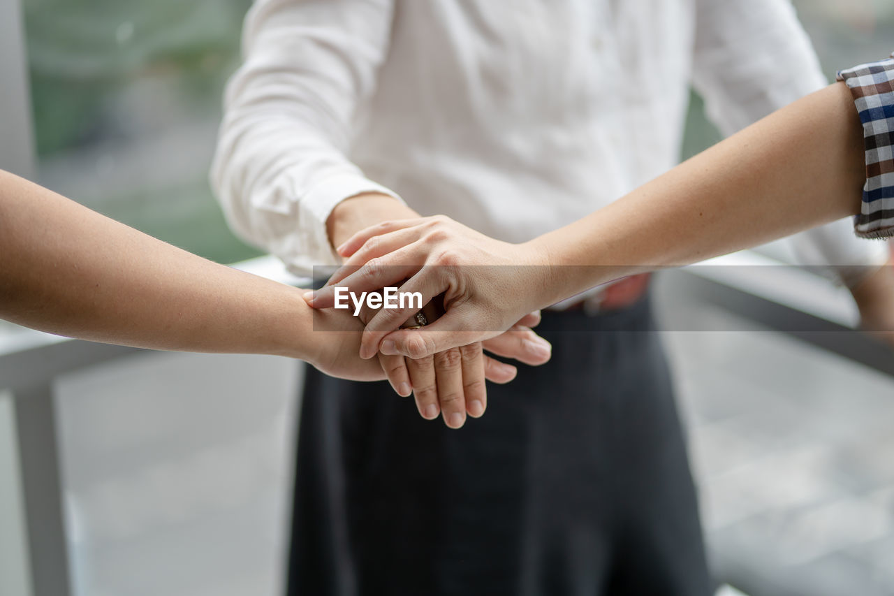 Cropped image of friends stacking hands