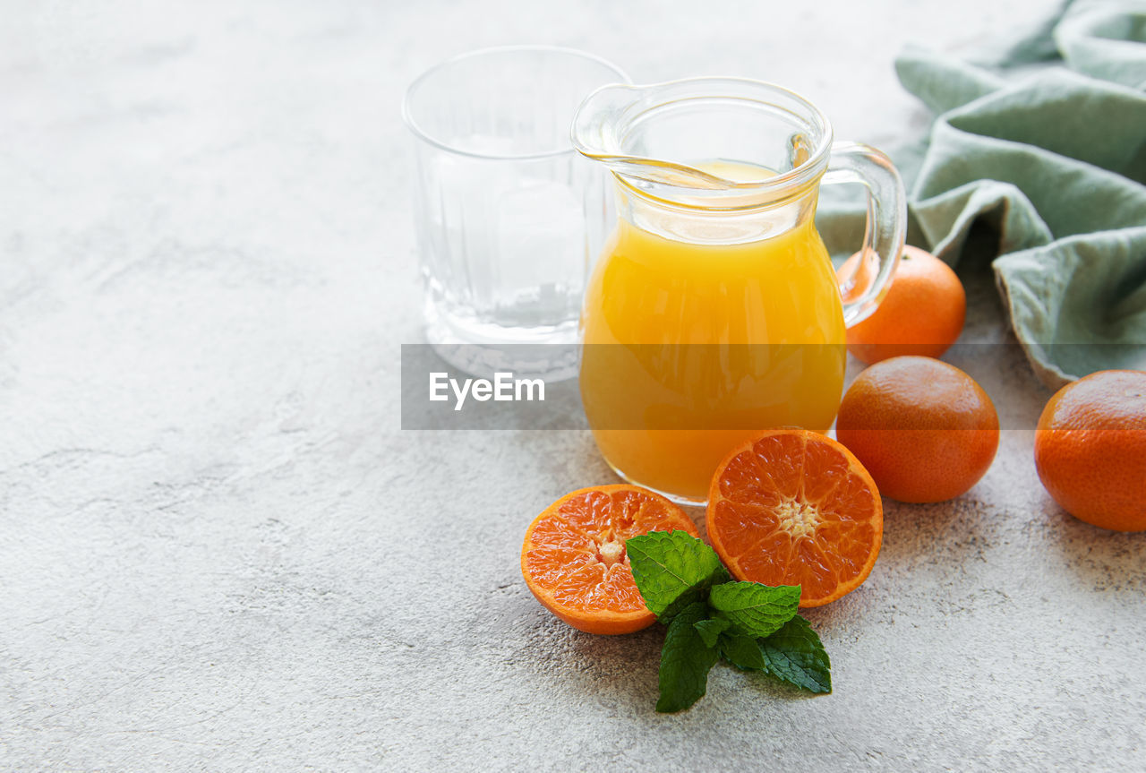 Jug of fresh orange tangerine juice with fresh fruits