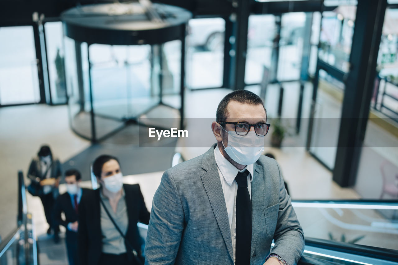 Business people moving upwards on escalator during pandemic