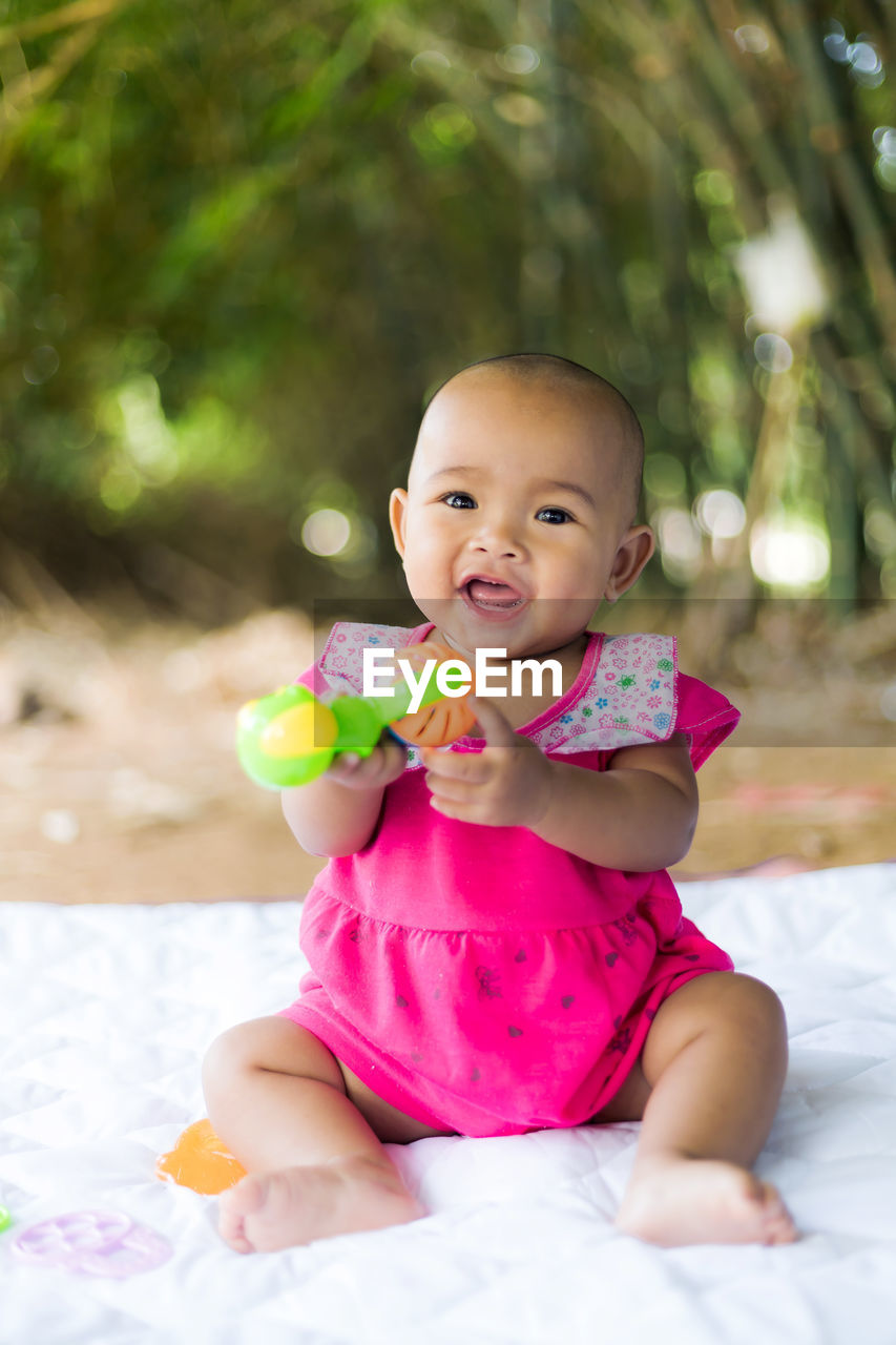 Portrait of cue baby girl sitting on blanket outdoor