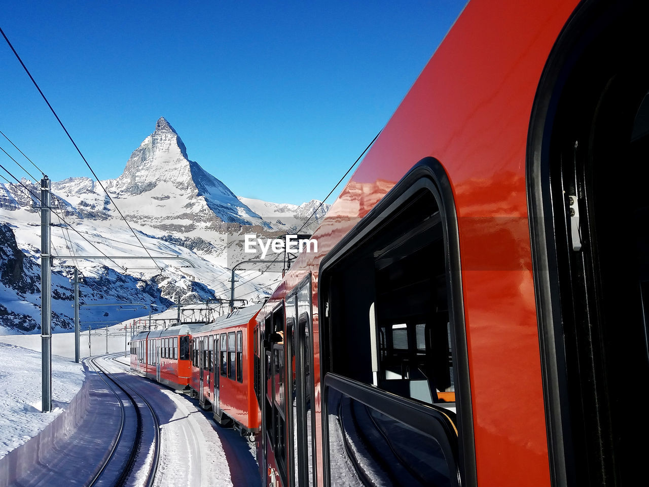 Train on snow covered mountain against blue sky, mt matherhorn switzerland