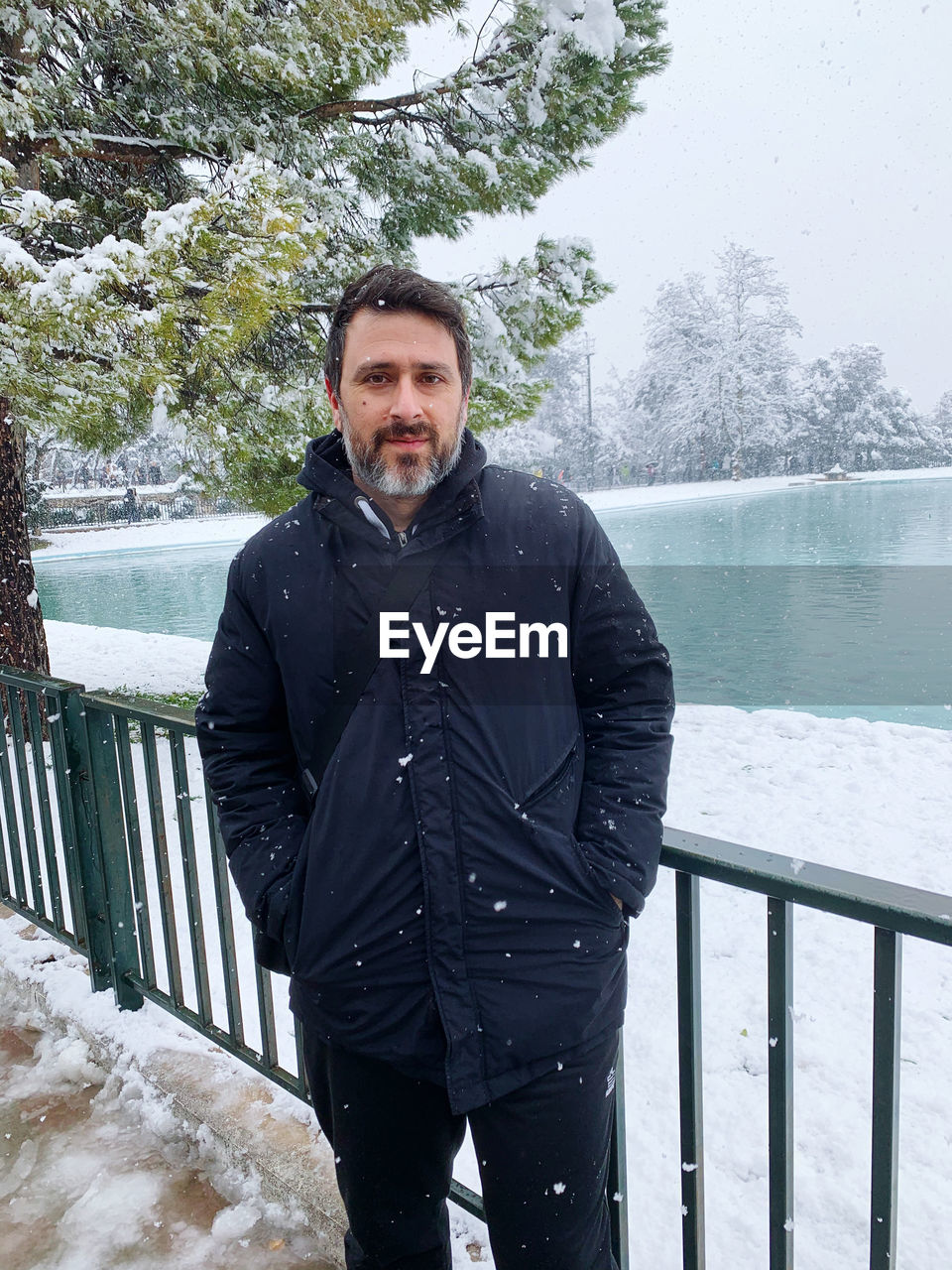 Portrait of young man standing against railing in winter