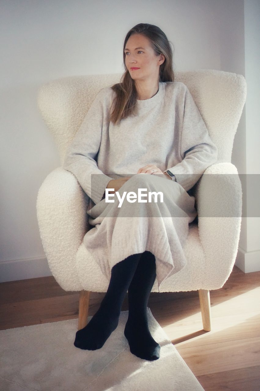 portrait of young woman sitting on chair at home