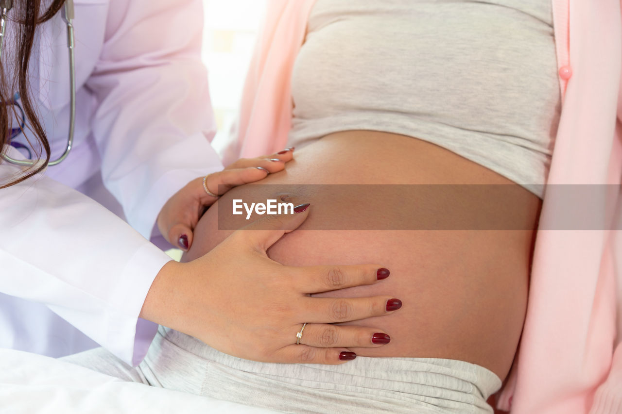 Midsection of pregnant woman getting examined by doctor