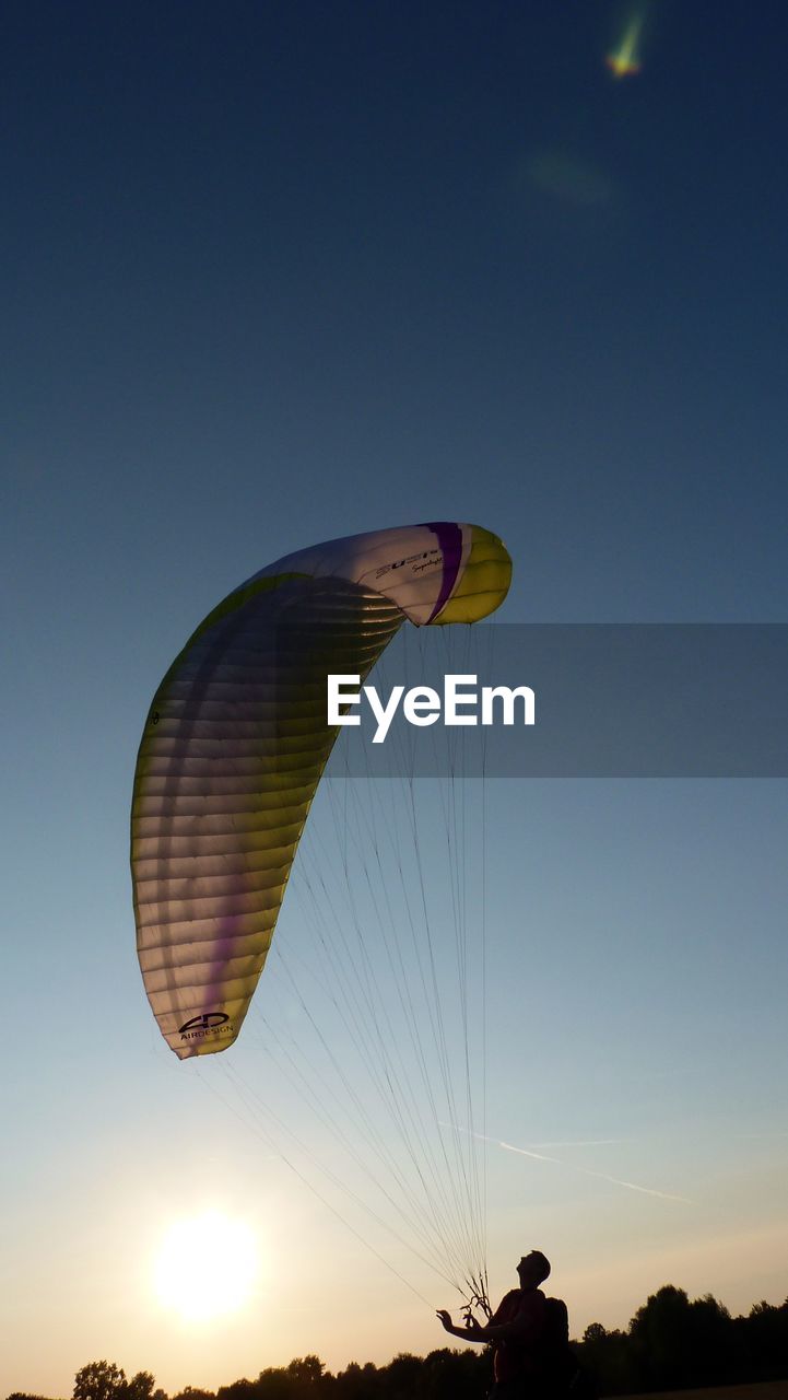 LOW ANGLE VIEW OF PERSON PARAGLIDING AGAINST CLEAR SKY