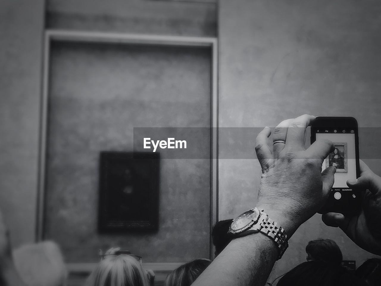 Cropped hand photographing mona lisa painting at museum