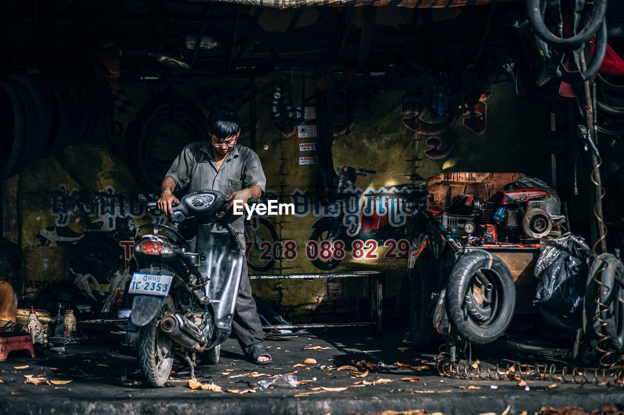 MAN WORKING ON MOTORCYCLE IN GARAGE