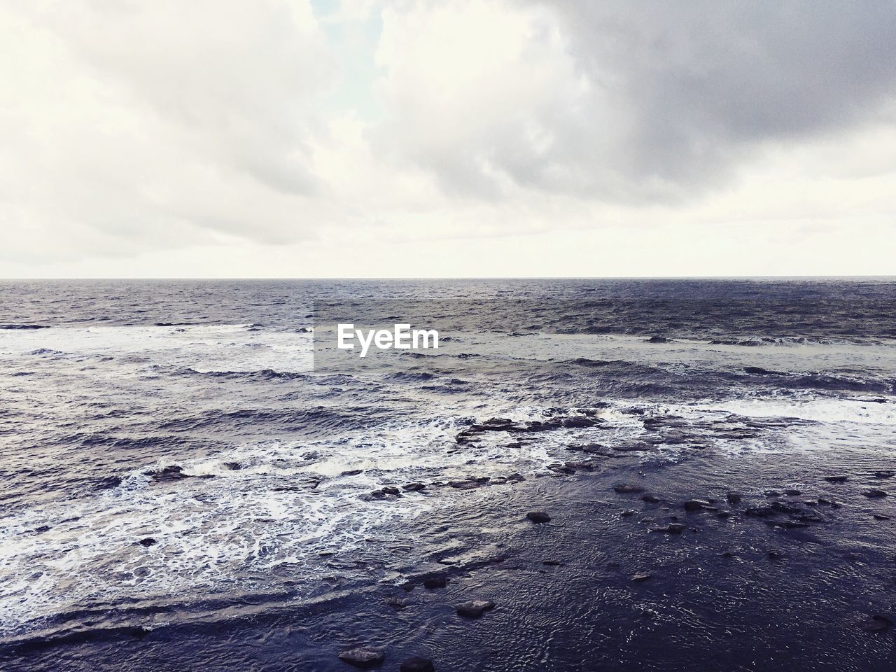 Scenic view of beach against cloudy sky