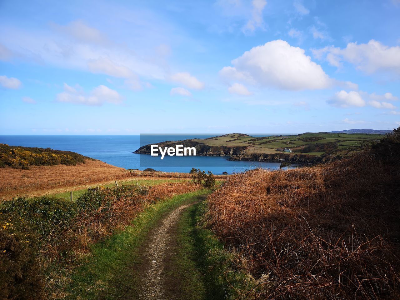 sky, coast, water, nature, sea, cloud, land, scenics - nature, hill, landscape, shore, horizon, beauty in nature, environment, plant, ocean, beach, tranquility, cliff, body of water, tranquil scene, grass, rural area, no people, travel destinations, travel, terrain, coastline, blue, horizon over water, tourism, outdoors, day, reservoir, non-urban scene, bay, island, footpath, rock, idyllic, holiday, road, rural scene, trip, vacation