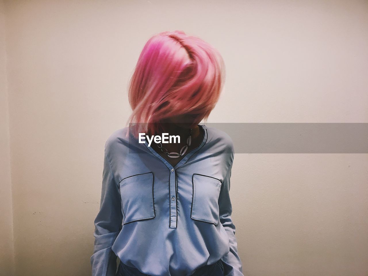 Woman with dyed hair standing against wall