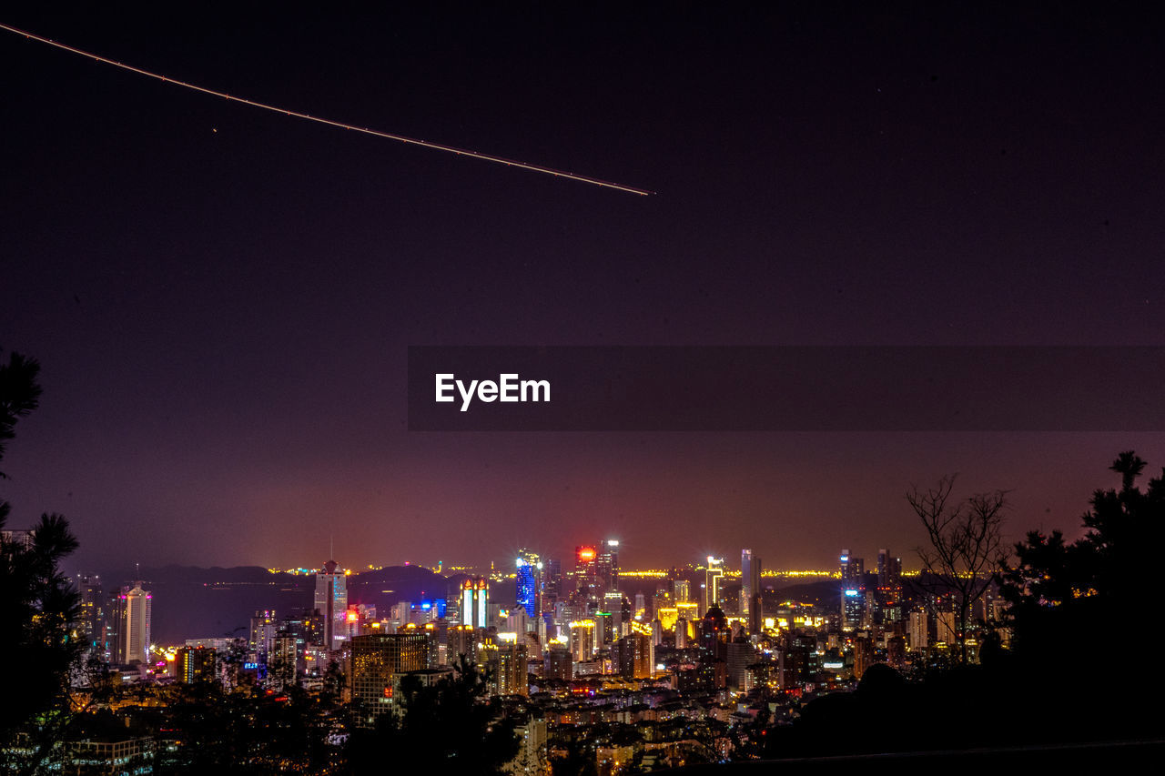 Illuminated cityscape against sky at night