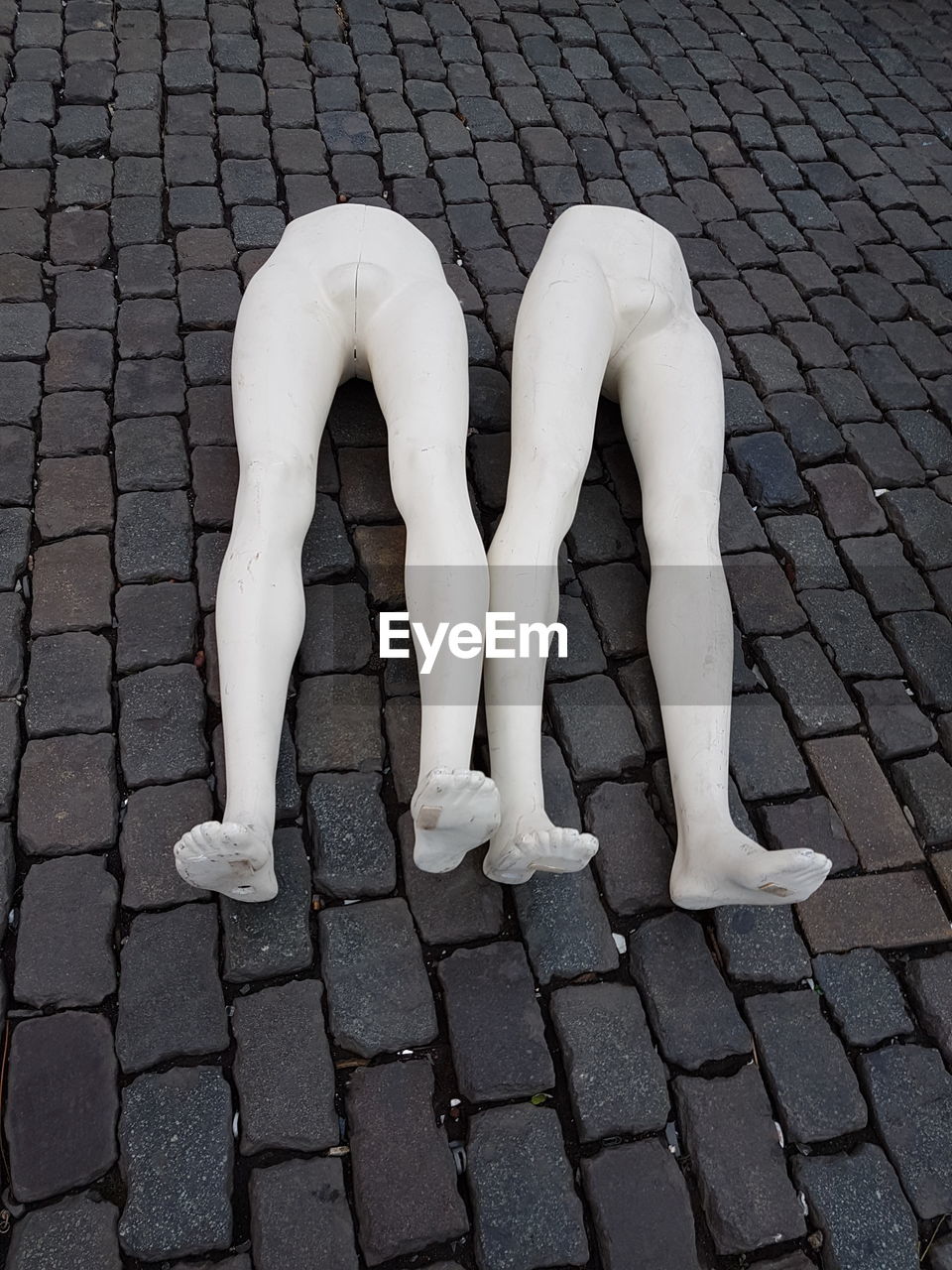 High angle view of broken mannequins on cobblestone street