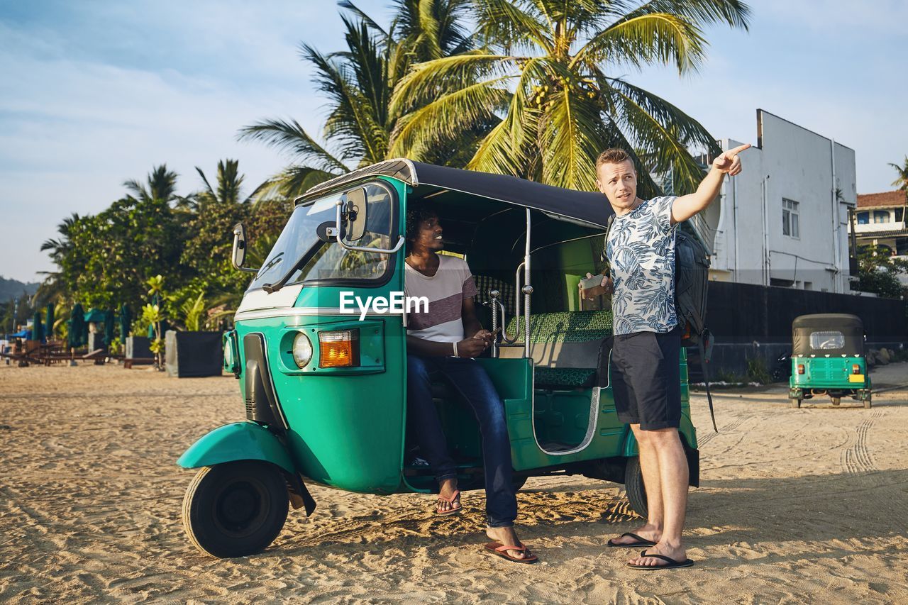 Men talking by rickshaw at beach